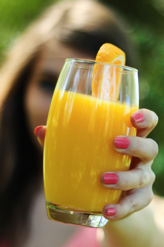 woman holding cup of orange juice