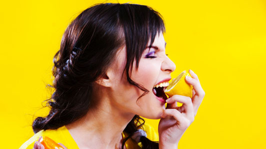 woman biting into lemon