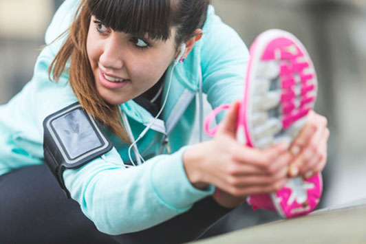 girl in pink running shoes stretching