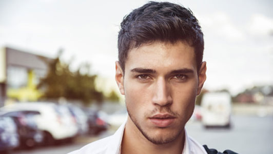 headshot of confident guy with suit over shoulder outdoors