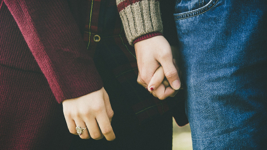 Couple interlocking their fingers.