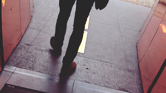 Legs of a guy in red shoes.