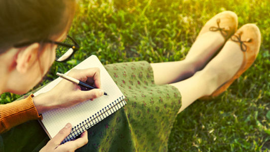 woman in glasses taking notes in green surrounding