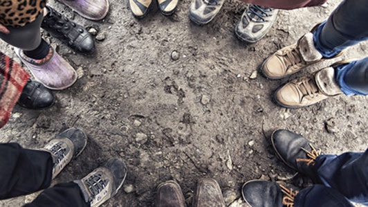 feet of people standing in a cirle outdoors