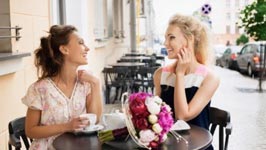 Two ladies sitting at a table, having coffee.