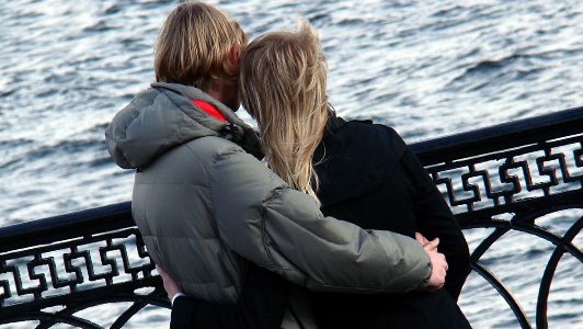 Couple hugging each other and looking at a sea.