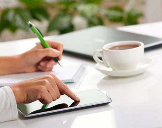 women taking notes touching smart device